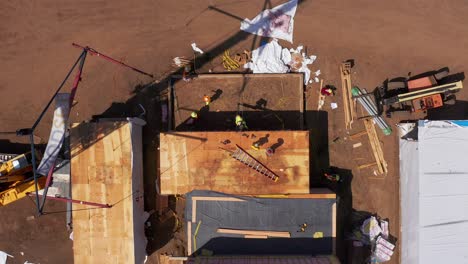 Bird's-eye-aerial-descending-shot-of-construction-crew-working-at-a-modular-housing-development-site-in-West-Los-Angeles,-California