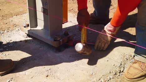 Gimbal-close-up-shot-of-construction-worker-using-a-wrench-and-sledgehammer-to-tighten-steel-nuts-and-bolts-at-a-modular-building-site-in-West-Los-Angeles,-California