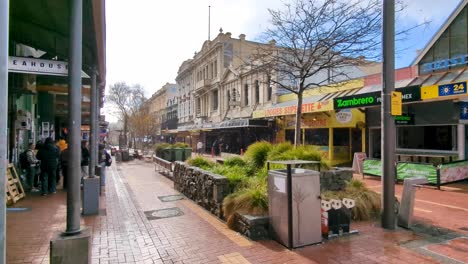 A-sudden-rain-shower-with-shoppers-sheltering-undercover-on-Cuba-Street-in-Wellington,-New-Zealand-Aotearoa