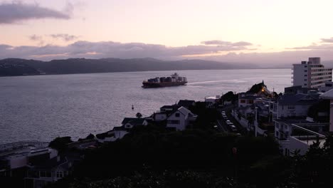 Early-morning-view-of-cargo-ship-with-shipping-containers-in-harbour-water-in-capital-city-of-Wellington,-New-Zealand-Aotearoa