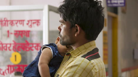 Close-up-shot-of-man-holding-child-in-his-arms-in-a-rural-hospital-in-India