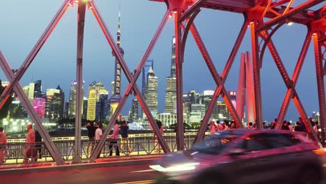 Tourists-gather-and-walk-along-metal-bridge-with-colorful-lights-to-admire-Shanghai-city-skyline