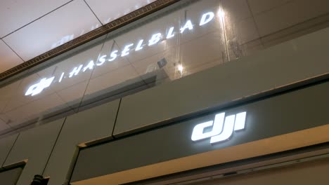 Los-Logotipos-De-La-Empresa-China-De-Tecnología-Dji-Y-Hasselblad-Se-Ven-En-Su-Tienda-Durante-La-Noche-En-Hong-Kong