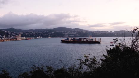 Cargo-ship-vessel-loaded-with-shipping-containers-coming-into-harbour-port-in-Wellington,-New-Zealand-Aotearoa