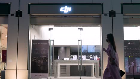 At-nighttime-in-Hong-Kong,-pedestrians-pass-by-the-DJI's-store,-renowned-for-its-drones