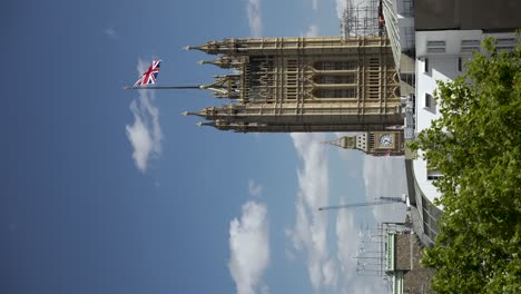 Victoria-tower-flying-the-Union-Flag-against-a-clear-blue-sky,-representing-UK's-history,-pride,-and-architectural-grandeur-with-a-touch-of-modern-urban-landscape