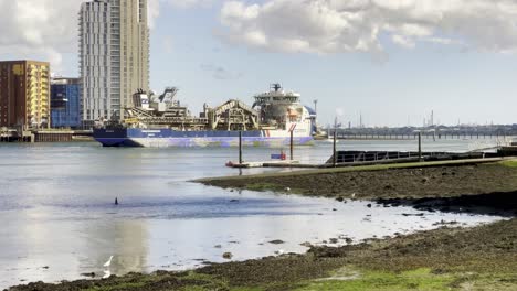 Cargo-ship-docked-in-an-industrial-harbor,-viewed-from-the-Summer-Feastival-by-Street-Food-Circus,-with-city-buildings-and-waterfront-in-the-background