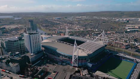 Cardiff-city-aerial-view-approaching-Welsh-Millennium-stadium-at-sunrise-across-capital-cityscape