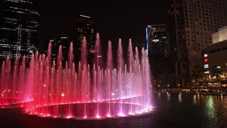 Mehrfarbige-Wassershow-In-Den-KLCC-Petronas-Twin-Towers-Mit-Der-Skyline-Von-Kuala-Lumpur-Im-Hintergrund,-Malaysia