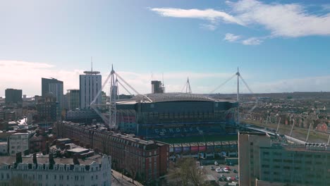 Vista-Aérea-En-Aumento-A-Través-Del-Estadio-Del-Milenio-De-La-Ciudad-De-Cardiff-Con-Salida-Del-Sol-Sobre-El-Paisaje-Urbano-De-La-Capital