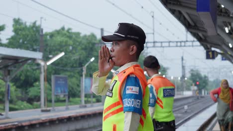 Indonesian-train-security-blowing-a-whistle-at-Sudimara-Train-Station,-Tangerang-Selatan