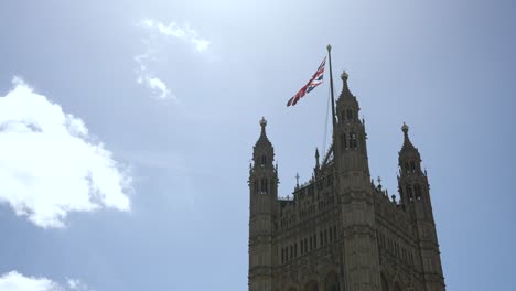 Blick-Hinauf-Zum-Victoria-Tower-Mit-Der-Union-Jack-Flagge,-Die-Am-Klaren-Himmel-Weht