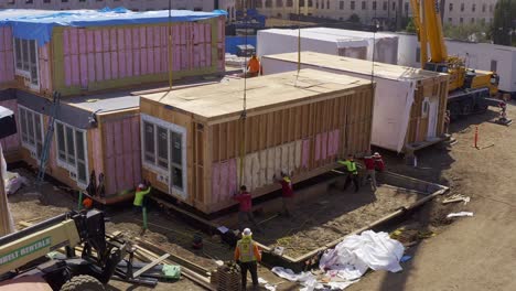 Descending-close-up-aerial-shot-of-a-heavy-duty-crane-lowering-a-housing-module-into-position-at-a-construction-site-in-West-Los-Angeles,-California