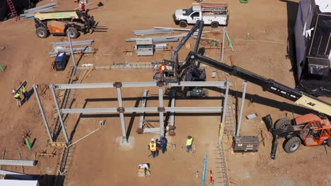 Aerial-wide-panning-shot-of-construction-workers-using-an-industrial-lift-crane-at-modular-housing-development-site-in-West-Los-Angeles,-California