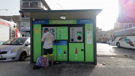 Old-man-drops-plastic-bottles-and-metal-cans-as-separated-waste-in-a-BCRS-reverse-vending-machine-for-refund-in-Birzabbuga,-Malta