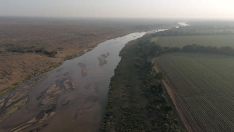 Hochfliegende-Drohnenansicht-Des-Saisonalen-Oder-Kurzlebigen-Crocodile-River-Durch-Ackerland-Am-Rande-Des-Krüger-Nationalparks