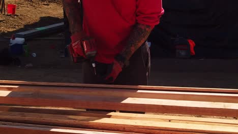 Construction-worker-drills-screws-into-lumber-at-a-pre-fabricated-housing-site-in-West-Los-Angeles,-California