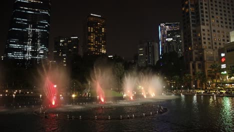 Espectáculo-De-Agua-De-Fuente-En-Las-Torres-Gemelas-Klcc-Petronas-Con-El-Paisaje-Urbano-De-Kuala-Lumpur-Al-Fondo,-Malasia