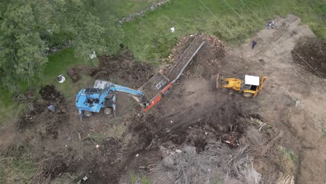 Drone-flight-where-we-see-the-work-carried-out-by-a-crusher-in-conjunction-with-2-other-machines-with-tree-pruning-remains,-we-observe-the-work-area-with-an-orbital-flight