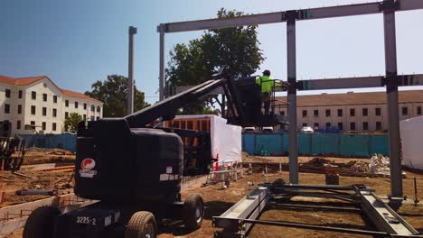 Gimbal-wide-panning-shot-of-a-bucket-lift-crane-at-a-modular-construction-site-in-West-Los-Angeles,-California