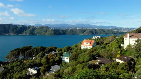 Houses-nestled-amongst-trees-in-the-hills-overlooking-harbour-water-towards-Miramar-Peninsula-in-Wellington,-New-Zealand-Aotearoa