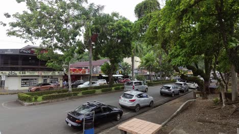 Off-season-street-view-of-the-Quepos-town-center-on-a-windy-day-with-cars,-traffic-and-local-restaurants-and-bars-in-the-background-in-Costa-Rica