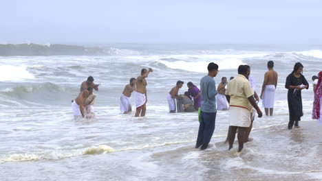 People-perform-the-'Bali-Tharpanam'-a-religious-ritual-for-their-departed-ancestors-on-no-moon-day-at-Papanasam-beach,-Varkala,-Kerala,-India