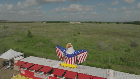 An-aerial-drone-view-of-a-fireworks-stand-with-a-large-inflatable-eagle-on-the-4th-of-July-in-Houston,-Texas