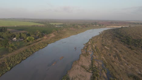 High-aerial-view-of-seasonal-or-ephemeral-crocodile-river-by-farmlands-bordering-the-Kruger-National-Park