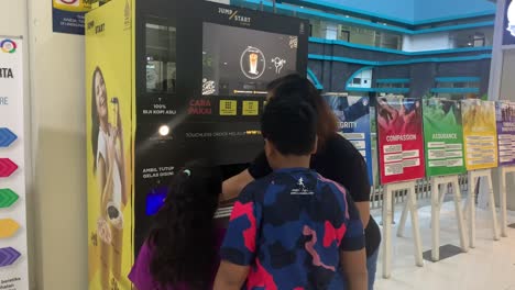 Familia-Comprando-Café-De-Una-Máquina-Automática-De-Bebidas