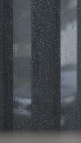 Real-rain-drops-sliding-on-window-glass,-vertical-view,-4K