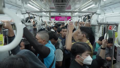 Tren-De-Cercanías-Lleno-De-Gente-Con-Pasajeros-De-Pie-Y-Agarrados-A-Los-Pasamanos-En-Tangerang-Selatan