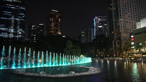 Blaue-Und-Grüne-Wassershow-In-Den-KLCC-Petronas-Twin-Towers-Mit-Der-Skyline-Von-Kuala-Lumpur-Im-Hintergrund,-Malaysia