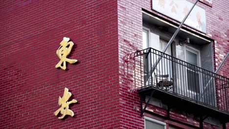 Red-tile-building-with-wrought-iron-balcony-and-gold-Chinese-characters-in-Philadelphia's-Chinatown