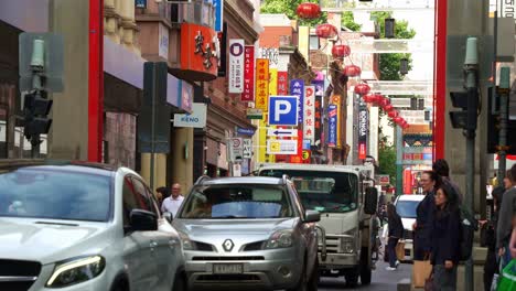 Melbourne-Chinatown-on-Little-Bourke-Street,-a-hub-of-activity-with-streets-lined-with-souvenir-shops-and-Chinese-eateries,-a-bustling-city-with-people-crossing-the-street-and-busy-vehicle-traffics