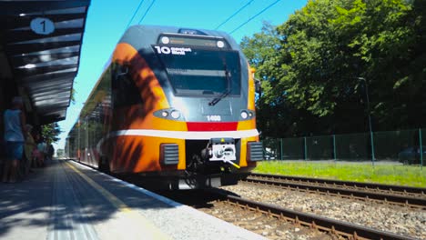 Ein-Orangefarbener-Zug-Der-Firma-Elron-Fährt-Im-Sommer-In-Den-Bahnhof-In-Tallinn,-Estland,-Europa-Ein,-Aufgenommen-In-4K