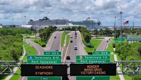 Port-Canaveral-Verkehrsschilder-Mit-Kreuzfahrtschiffen-Und-Amerikanischer-Flagge-Im-Hintergrund