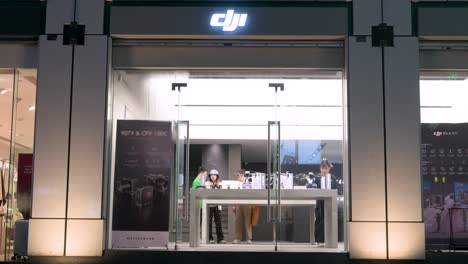 Customers-shop-at-the-Chinese-technology-company-DJI's-official-store,-known-for-its-drone-product-line-and-video-camera-gear,-during-nighttime-in-Hong-Kong