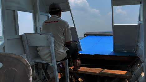 Boat-captain-sitting-down-piloting-his-craft,-wide-interior