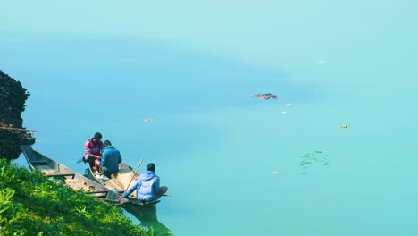 Fischer-Auf-Einem-Boot-Am-Flussufer-Mit-Adlern-Und-Falken,-Die-Fliegen-Und-Totes-Tierfleisch-Fressen