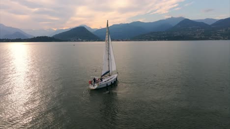 Sailboat-is-turning-on-a-mountain-lake-at-sunset,-creating-a-peaceful-and-scenic-view