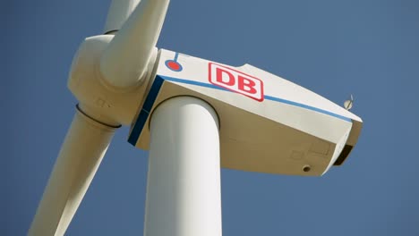 Close-up-of-a-wind-turbine-with-the-Deutsche-Bahn-logo-against-a-clear-blue-sky