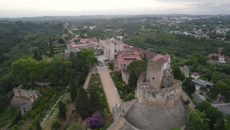 Convent-of-christ-in-tomar,-portugal-with-surrounding-lush-greenery-and-historical-architecture,-aerial-view