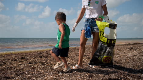 Slow-motion-of-a-brunette-mexican-mother-committed-with-the-environment-teaching-her-son-te-keep-the-beaches-clean