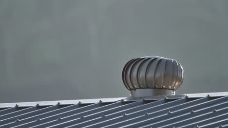 Close-up,-A-whirlybird-turning-from-the-wind-in-the-morning-sunshine-on-a-metal-shed-roof,-Townsville,-Queensland