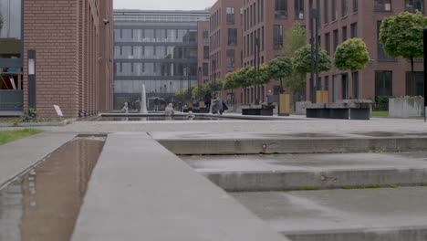 Panning-shot-of-a-modern-urban-square-with-people-walking-and-interacting,-shot-during-the-day