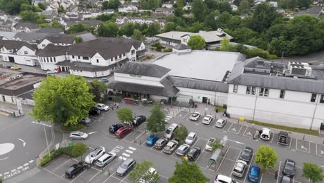 Aerial-view-of-a-Waitrose-supermarket-and-parking-lot-in-Okehampton-Devon-UK,-surrounded-by-residential-buildings,-July-2024