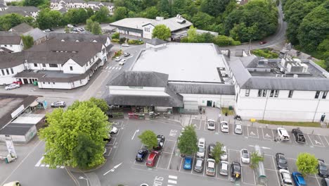 Drone-view-of-Waitrose-supermarket-store-in-Okehampton-Devon-UK,-with-surrounding-parking-area-and-greenery,-July-2024