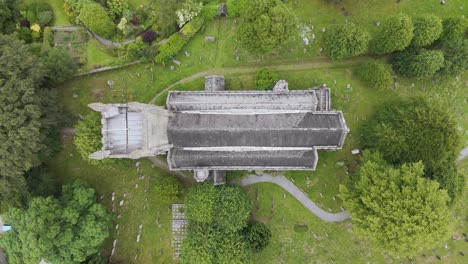 Top-down-aerial-view-of-All-Saints-Church-outside-of-Okehampton-in-Devon-UK,-surrounded-by-greenery-and-cemetery,-July-2024