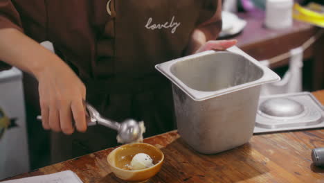 Eine-Nahaufnahme-Der-Künstlerischen-Hand-Eines-Kochs,-Der-Mit-Einer-Zufriedenstellenden-Kugel-Aus-Einem-Edelstahllöffel-Perfekt-Runde-Eiskugeln-Herstellt